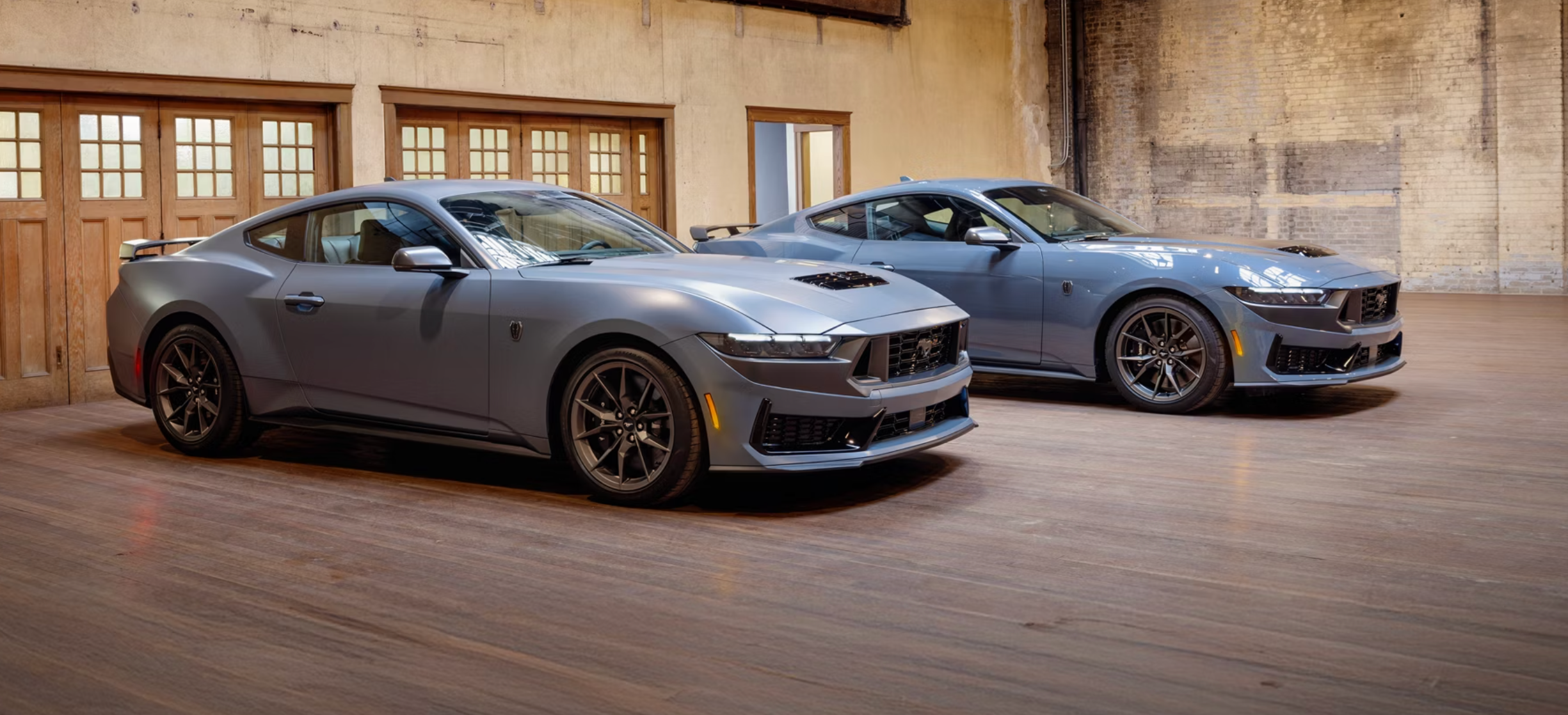 Two new gray 2026 Ford Mustangs in showroom near Caldwell, OH